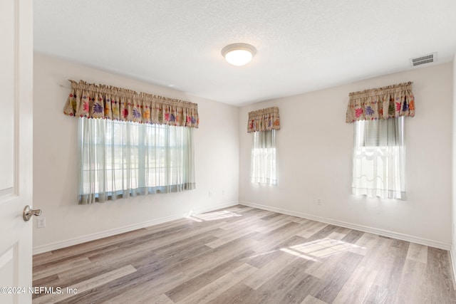 spare room featuring a textured ceiling and light wood-type flooring