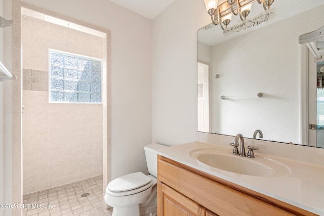 bathroom featuring vanity, a tile shower, and toilet