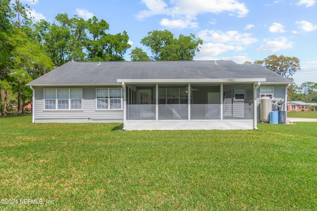 rear view of house featuring a yard and a sunroom