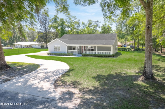 ranch-style home featuring covered porch and a front lawn