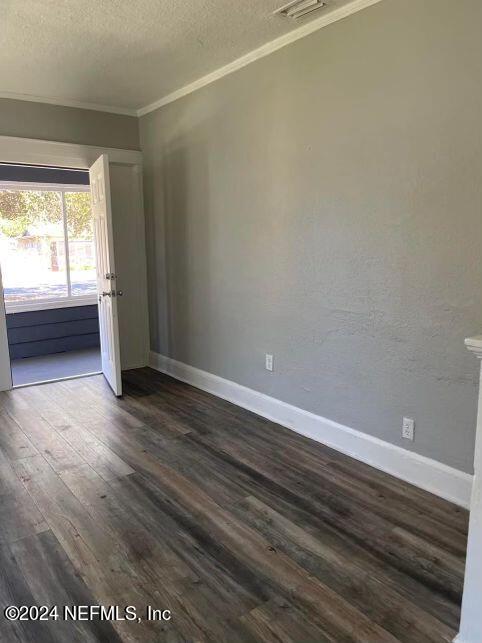 spare room with crown molding, dark hardwood / wood-style flooring, and a textured ceiling