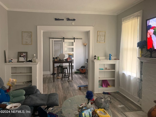 living room with a barn door, crown molding, dark wood-type flooring, and a wealth of natural light