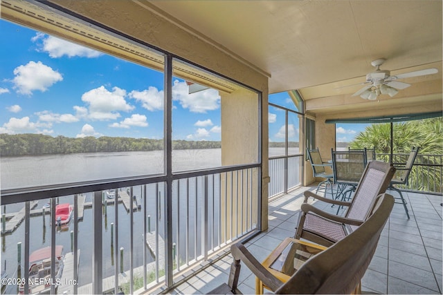 sunroom / solarium featuring ceiling fan and a water view