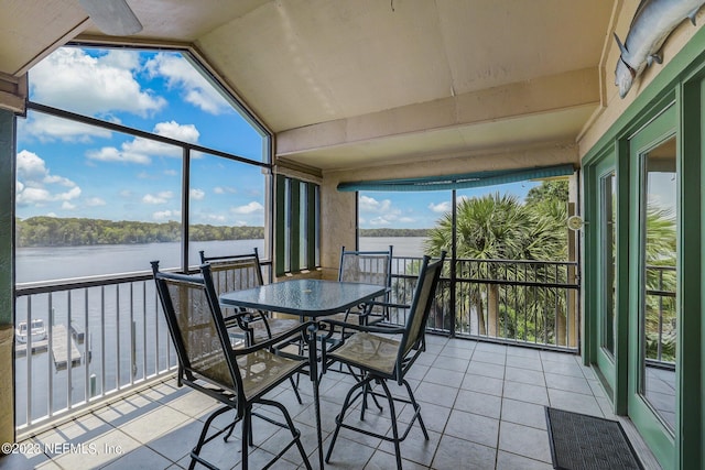 sunroom with a healthy amount of sunlight, a water view, and lofted ceiling