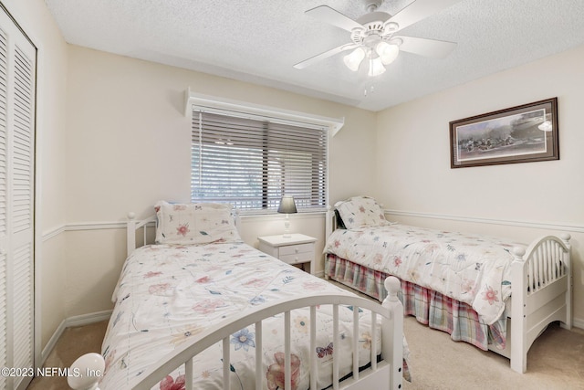 bedroom with light carpet, a closet, ceiling fan, and a textured ceiling