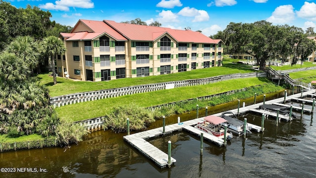 dock area featuring a water view, a balcony, and a lawn