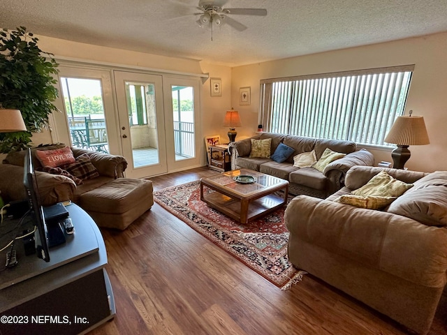 living room featuring wood-type flooring, a textured ceiling, ceiling fan, and french doors