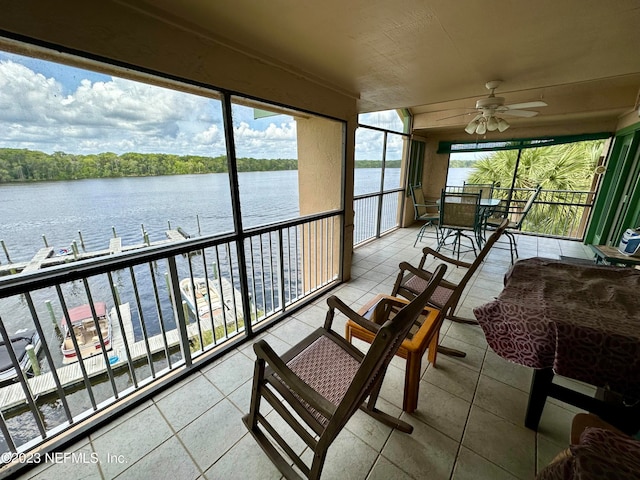 sunroom with ceiling fan and a water view