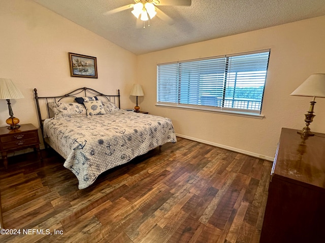 bedroom with a textured ceiling, dark wood-type flooring, ceiling fan, and vaulted ceiling