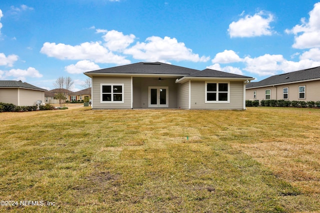 rear view of house featuring ceiling fan, a lawn, and french doors