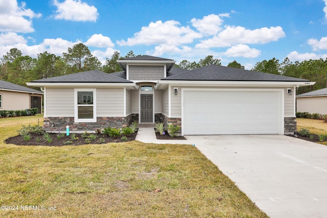 prairie-style house with concrete driveway, stone siding, a front lawn, and an attached garage