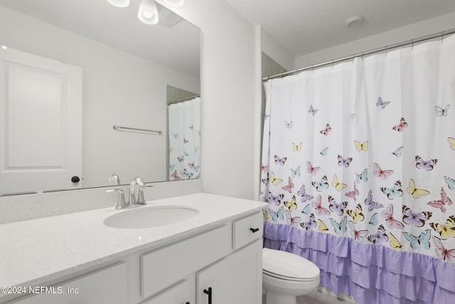 bathroom featuring a shower with shower curtain, vanity, toilet, and a textured ceiling