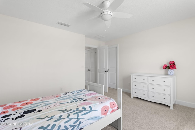 bedroom with baseboards, visible vents, a ceiling fan, light colored carpet, and a textured ceiling