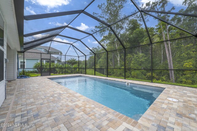 view of pool featuring glass enclosure and a patio