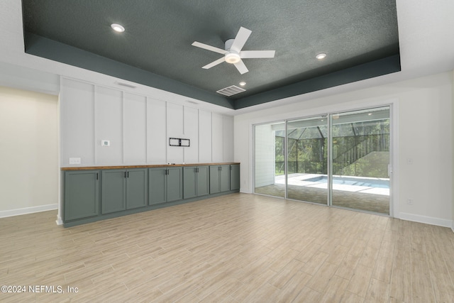 unfurnished room with light wood finished floors, a tray ceiling, and visible vents