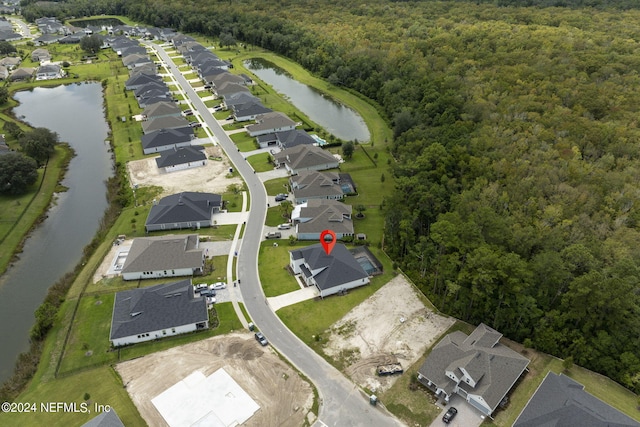 drone / aerial view featuring a water view, a residential view, and a view of trees