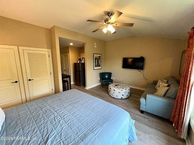 bedroom featuring ceiling fan, black refrigerator, and hardwood / wood-style floors