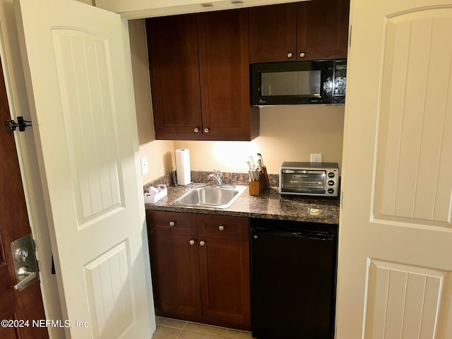 kitchen featuring sink, light tile patterned flooring, dark brown cabinets, dark stone counters, and black appliances