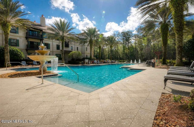 view of swimming pool with pool water feature and a patio area