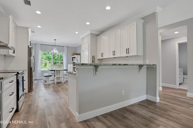 kitchen with light stone counters, light hardwood / wood-style flooring, a breakfast bar, white cabinets, and appliances with stainless steel finishes