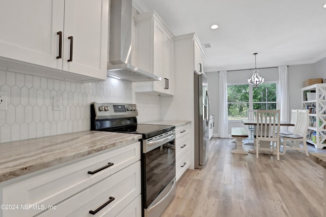 kitchen featuring decorative backsplash, light stone counters, stainless steel appliances, wall chimney range hood, and white cabinets