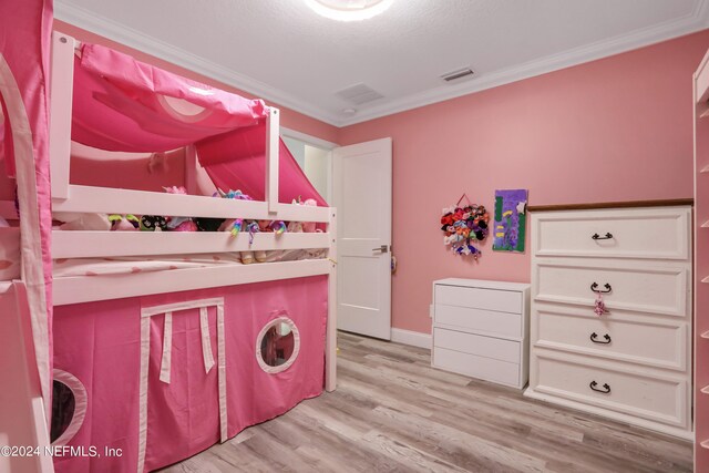 clothes washing area featuring crown molding and light hardwood / wood-style floors