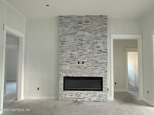 unfurnished living room featuring concrete flooring and a stone fireplace