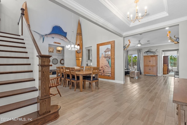 dining room featuring ceiling fan with notable chandelier, a raised ceiling, crown molding, and light hardwood / wood-style flooring