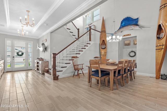 dining space with a tray ceiling, ornamental molding, a notable chandelier, and light wood-type flooring