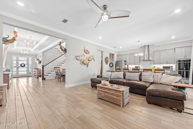 living room featuring ceiling fan with notable chandelier, light hardwood / wood-style floors, and crown molding