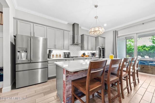 kitchen with a center island with sink, wall chimney exhaust hood, gray cabinetry, and stainless steel appliances