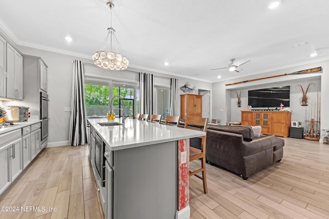 kitchen with gray cabinets, sink, a center island with sink, and light hardwood / wood-style flooring