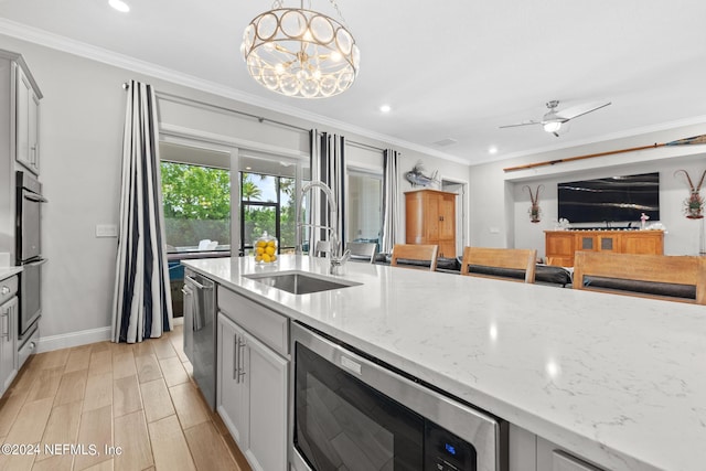 kitchen with hanging light fixtures, light stone counters, sink, and stainless steel appliances