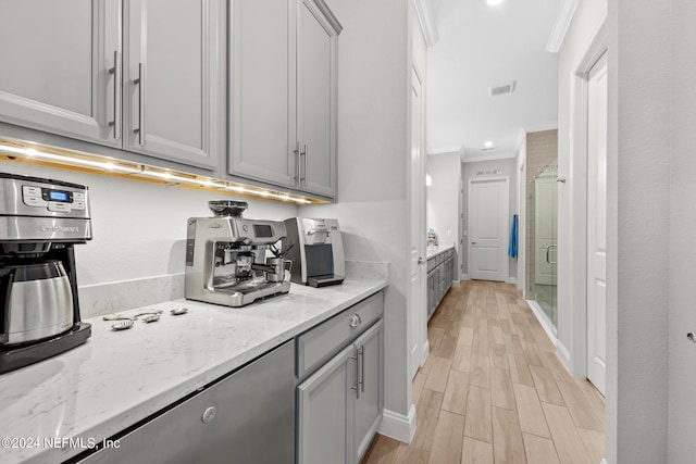 kitchen featuring gray cabinets, light stone counters, ornamental molding, and light hardwood / wood-style floors