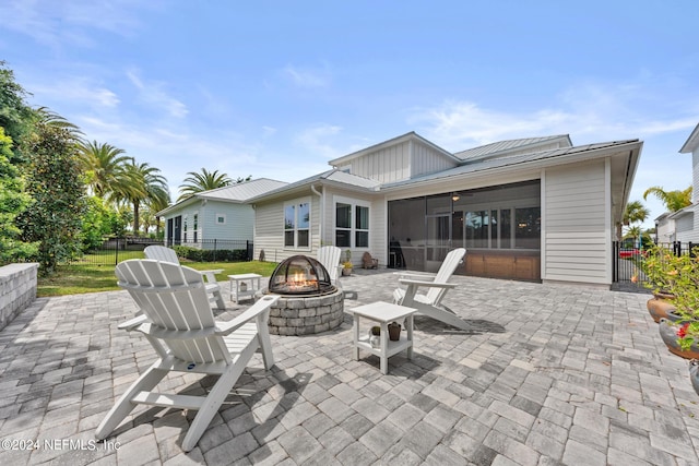 view of patio / terrace with a sunroom, ceiling fan, and an outdoor fire pit