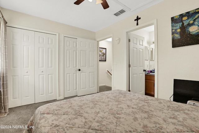 carpeted bedroom featuring ceiling fan, two closets, and ensuite bathroom