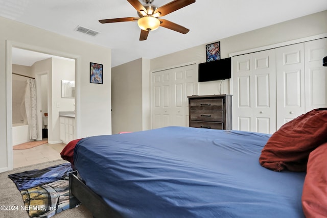 tiled bedroom with ensuite bath, ceiling fan, and two closets