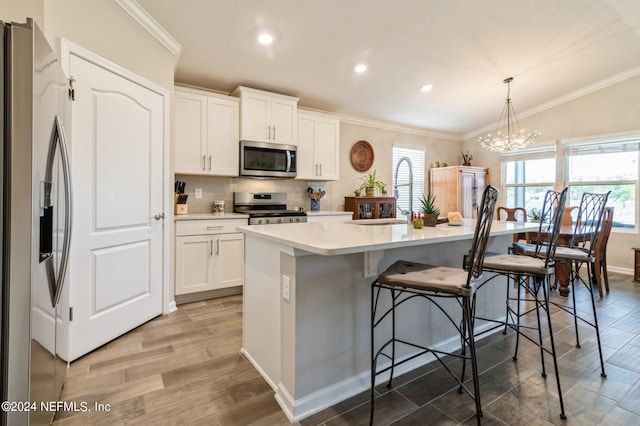 kitchen with a kitchen island with sink, stainless steel appliances, a sink, ornamental molding, and backsplash