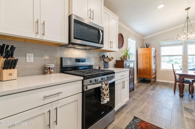 kitchen with tasteful backsplash, light wood-style flooring, ornamental molding, stainless steel appliances, and white cabinetry