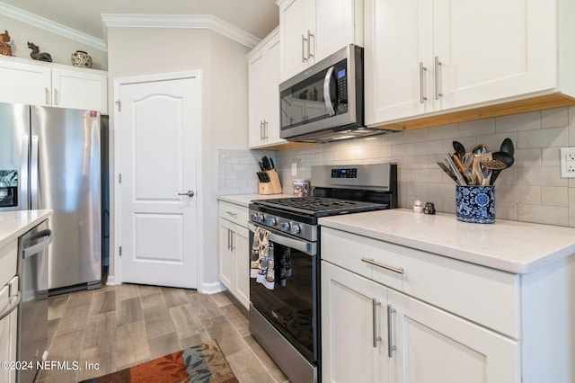 kitchen featuring ornamental molding, appliances with stainless steel finishes, light wood finished floors, and white cabinetry