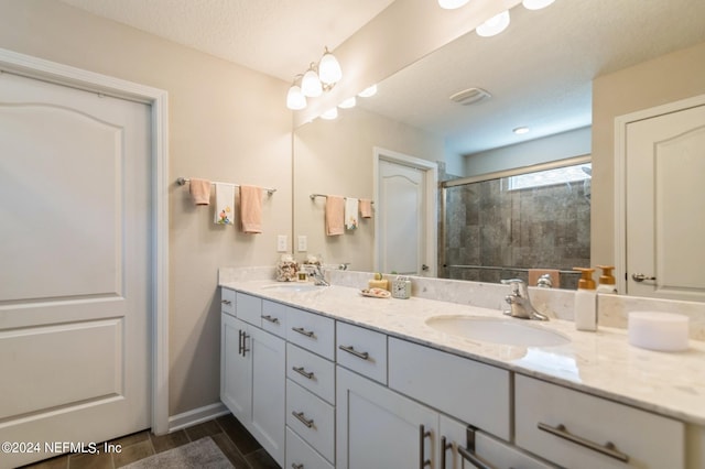 full bath featuring a stall shower, a sink, baseboards, and double vanity