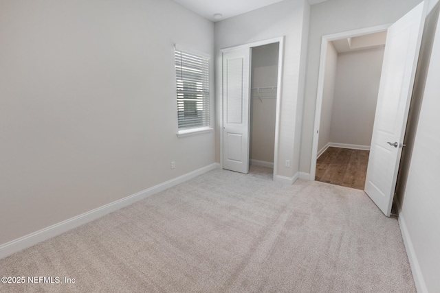 unfurnished bedroom featuring baseboards, a closet, and light colored carpet