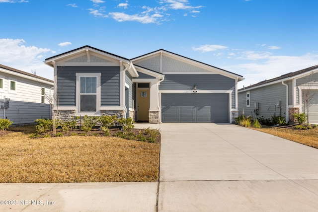 craftsman inspired home with driveway, stone siding, an attached garage, and a front yard