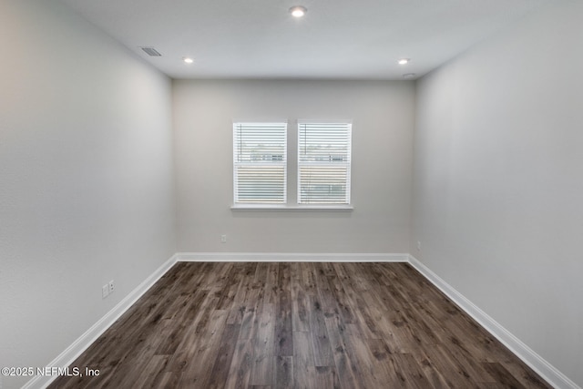 empty room with recessed lighting, dark wood finished floors, visible vents, and baseboards