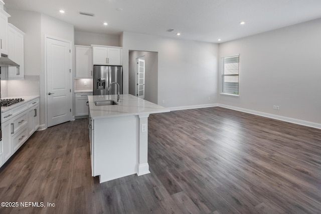 kitchen with stainless steel appliances, a sink, visible vents, white cabinetry, and a center island with sink