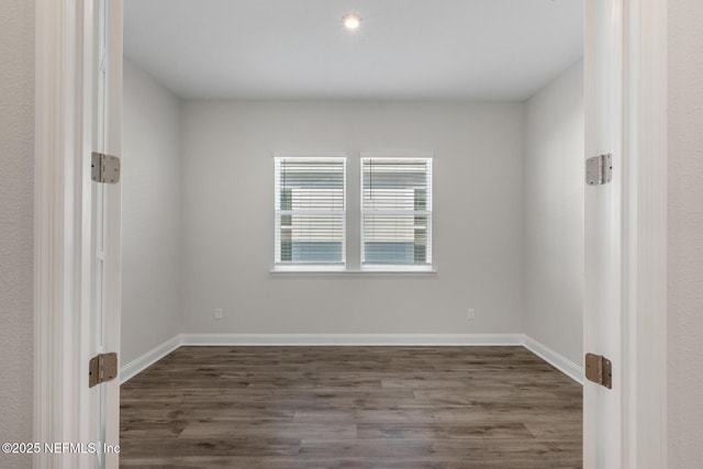 empty room with dark wood-type flooring and baseboards