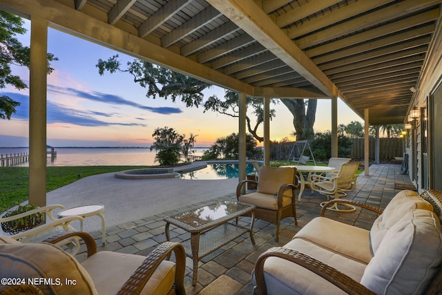 patio terrace at dusk featuring a fenced in pool, an outdoor living space, and a water view