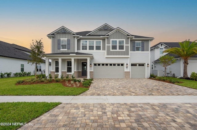 view of front of house featuring a porch, a garage, and a yard