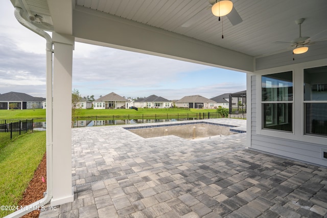 view of patio with ceiling fan, a water view, and a fenced in pool