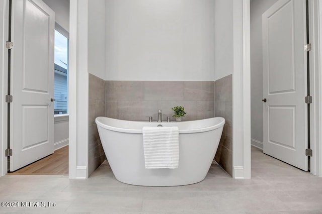 bathroom featuring a wealth of natural light, a washtub, and tile walls